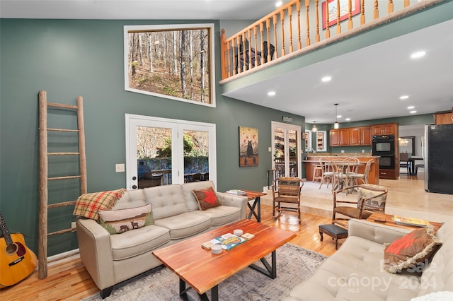 living room with light hardwood / wood-style flooring and high vaulted ceiling