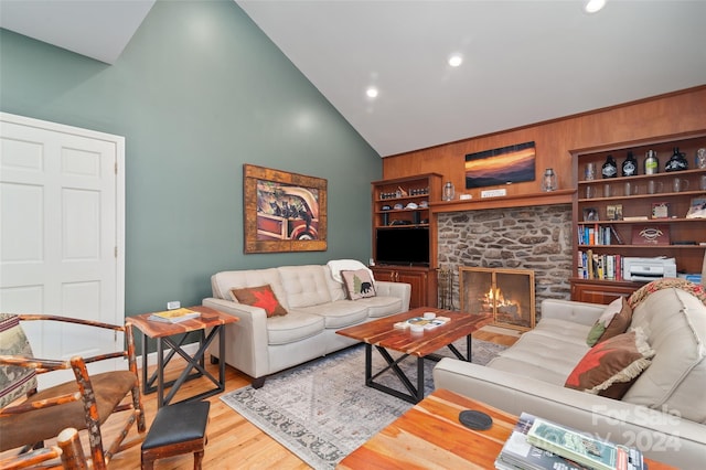 living room featuring wooden walls, a fireplace, high vaulted ceiling, and hardwood / wood-style floors