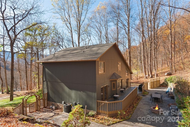 view of side of property with central AC unit, a patio area, and an outdoor fire pit