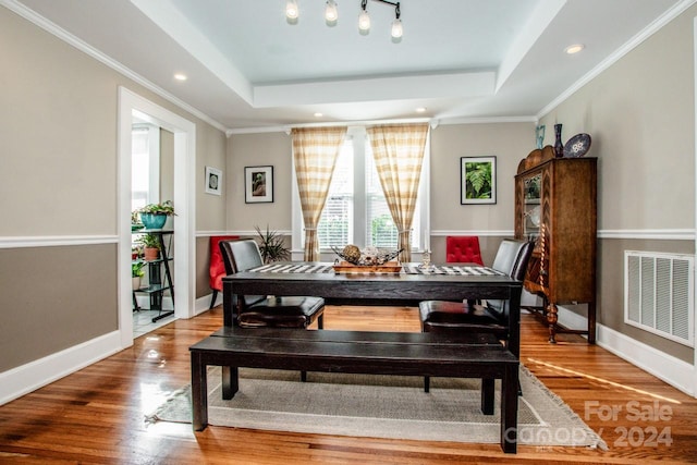 dining area with ornamental molding, hardwood / wood-style floors, and a tray ceiling