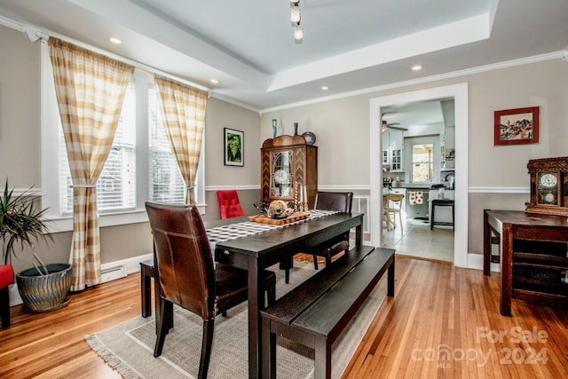 dining space featuring ornamental molding, light hardwood / wood-style flooring, ceiling fan, and a tray ceiling