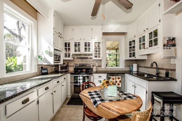 kitchen featuring dark stone counters, sink, light tile patterned flooring, white cabinetry, and appliances with stainless steel finishes