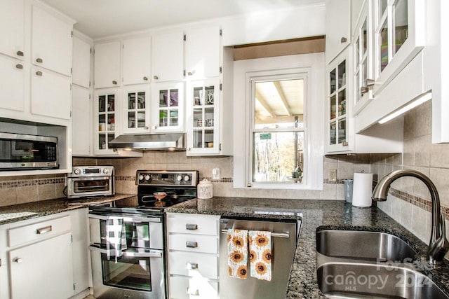 kitchen with stainless steel appliances, dark stone countertops, and white cabinetry