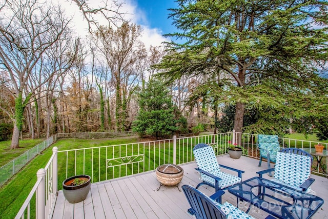 wooden terrace featuring a yard and a fire pit