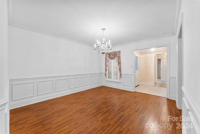 unfurnished room featuring ornamental molding, an inviting chandelier, and light hardwood / wood-style floors