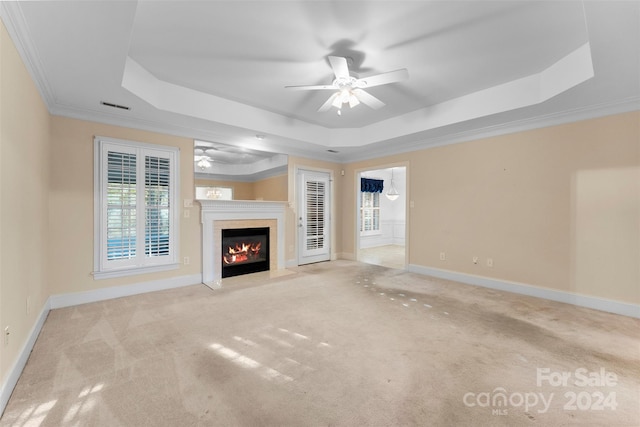 unfurnished living room featuring crown molding, a premium fireplace, light carpet, and a raised ceiling