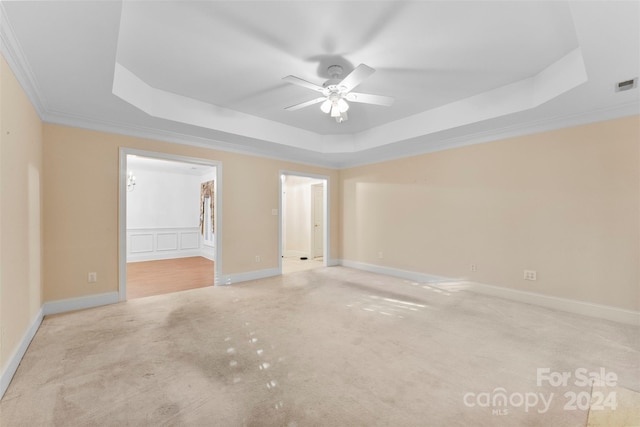 carpeted empty room featuring ceiling fan, a tray ceiling, and ornamental molding