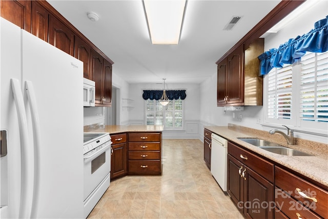 kitchen featuring white appliances, a notable chandelier, hanging light fixtures, sink, and kitchen peninsula