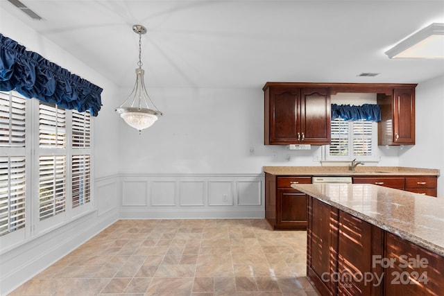 kitchen with sink, light stone countertops, dark brown cabinets, pendant lighting, and dishwasher