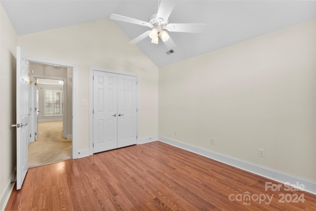 unfurnished bedroom with light wood-type flooring, ceiling fan, high vaulted ceiling, and a closet