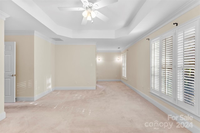 carpeted empty room featuring a tray ceiling, ceiling fan, and crown molding