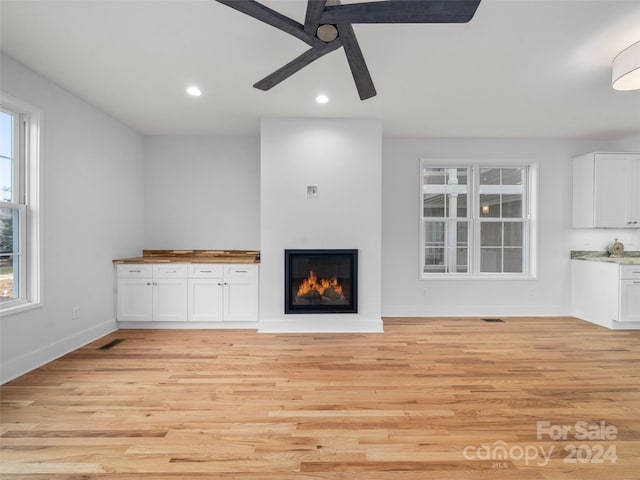 unfurnished living room featuring ceiling fan, light hardwood / wood-style floors, and plenty of natural light