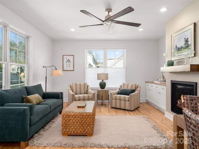 living room with a glass covered fireplace, a healthy amount of sunlight, recessed lighting, and light wood-type flooring
