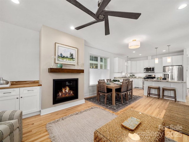 dining area with recessed lighting, ceiling fan, light wood-style flooring, and a glass covered fireplace