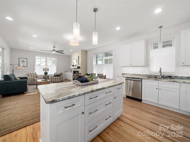 kitchen featuring open floor plan, a sink, light wood-style floors, and stainless steel dishwasher