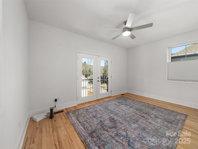 empty room featuring baseboards, wood finished floors, ceiling fan, and french doors