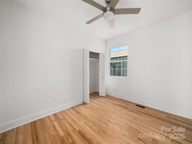 unfurnished bedroom with light wood finished floors, baseboards, visible vents, and a closet