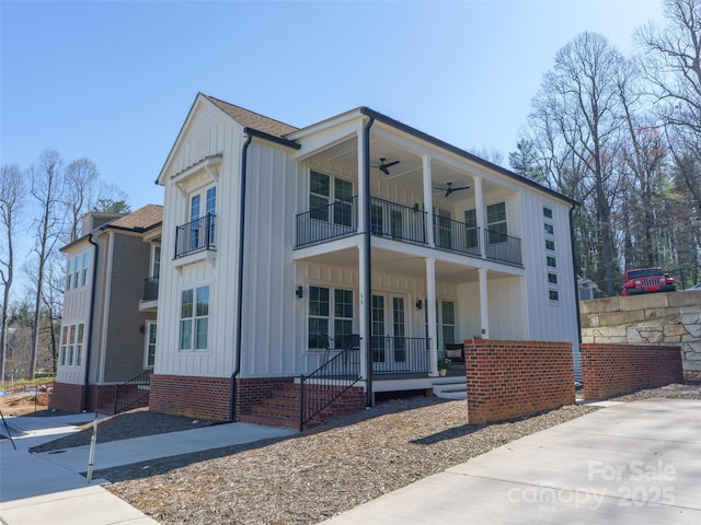 view of front of house featuring board and batten siding, a balcony, roof with shingles, and ceiling fan