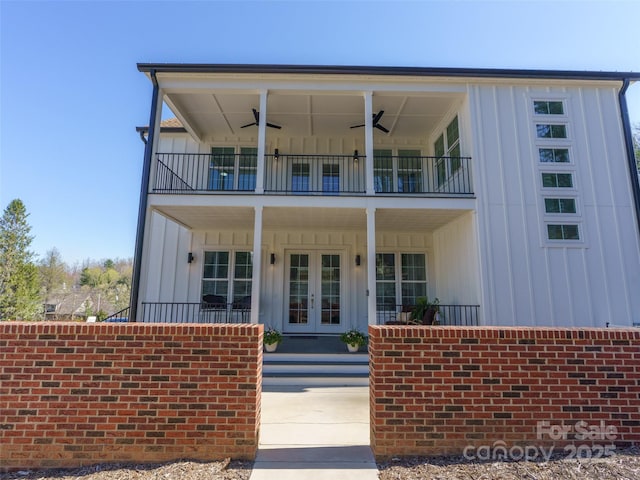 view of front of house with french doors, board and batten siding, a balcony, and ceiling fan