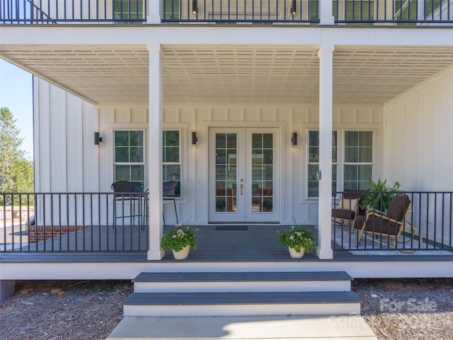 property entrance featuring covered porch, board and batten siding, a balcony, and french doors