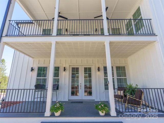 view of exterior entry with a balcony, board and batten siding, and french doors