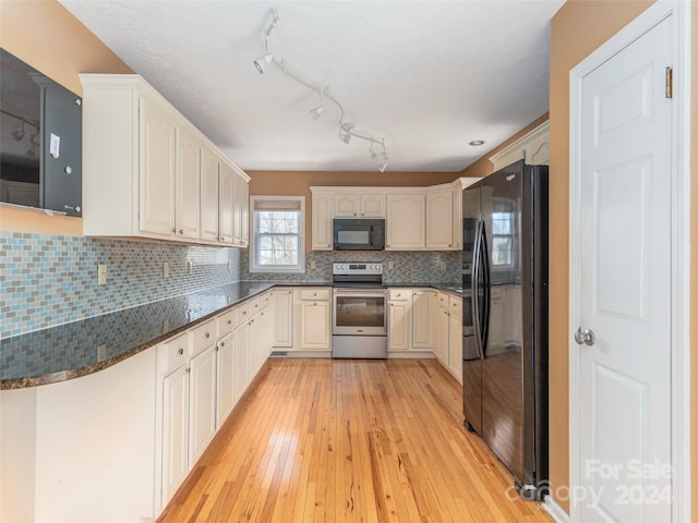 kitchen featuring black appliances, backsplash, light wood-type flooring, and dark stone counters