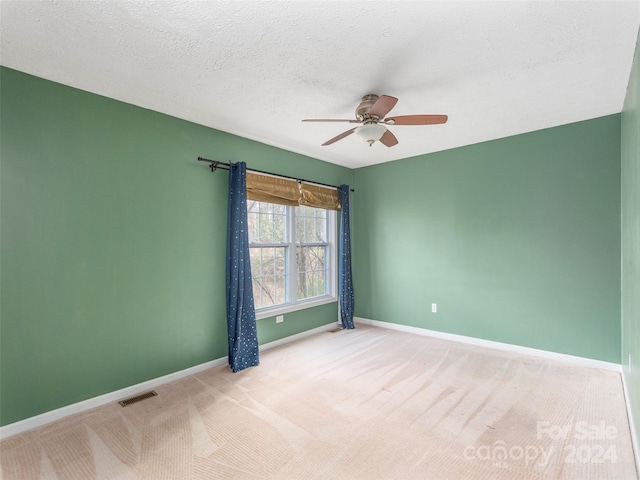 empty room with light carpet, a textured ceiling, and ceiling fan