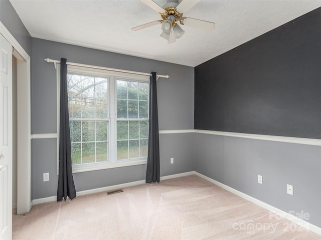 carpeted spare room with a textured ceiling and ceiling fan