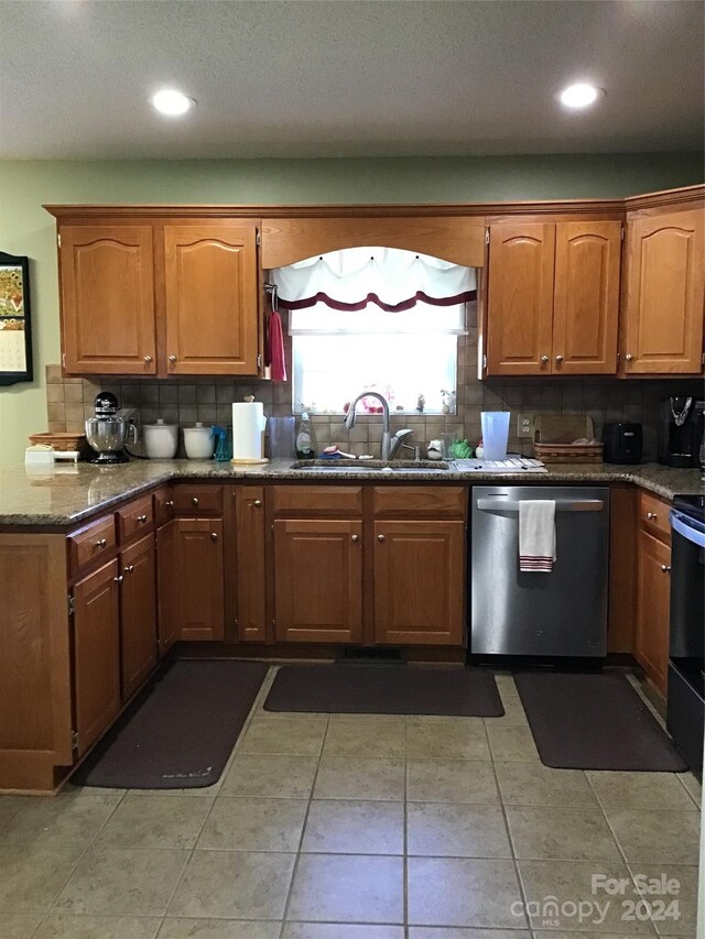 kitchen with dishwasher, sink, dark stone counters, and tasteful backsplash