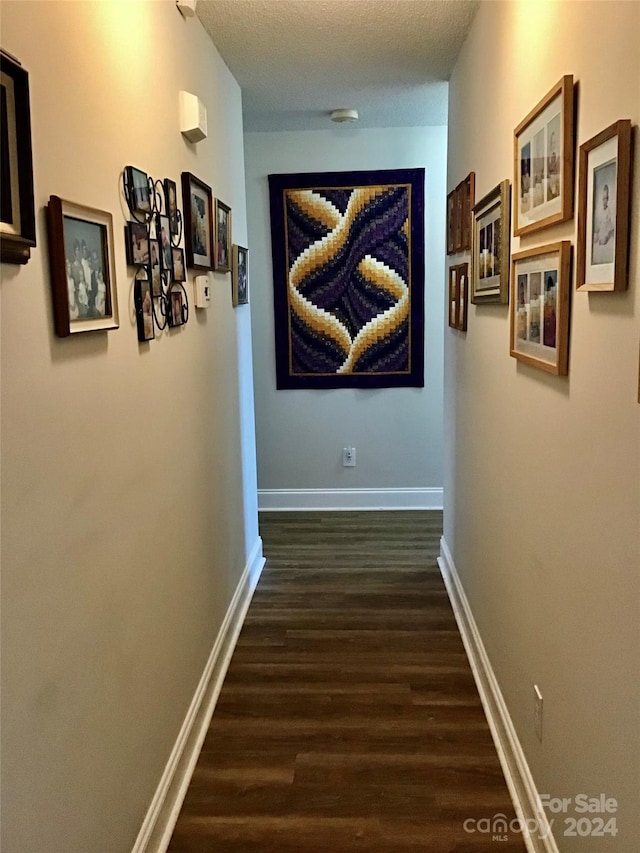 corridor with dark hardwood / wood-style floors and a textured ceiling