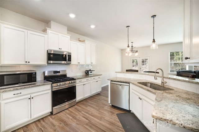 kitchen with sink, white cabinetry, tasteful backsplash, pendant lighting, and stainless steel appliances