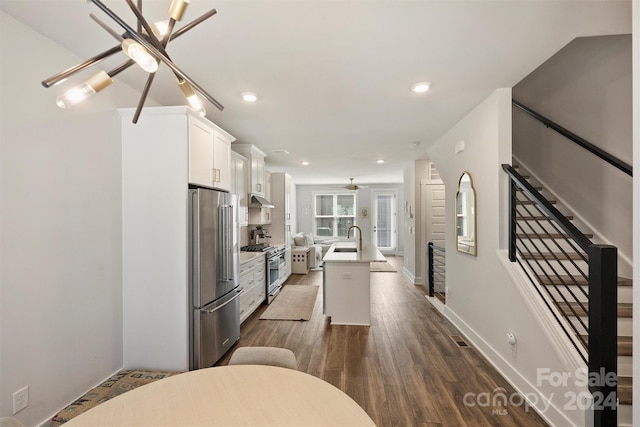 kitchen with a center island with sink, white cabinetry, premium appliances, dark hardwood / wood-style flooring, and sink