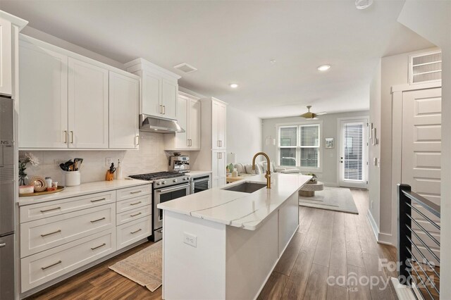 kitchen with dark hardwood / wood-style flooring, appliances with stainless steel finishes, sink, and a center island with sink