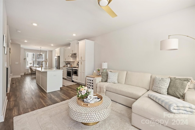 living room featuring dark wood-type flooring, ceiling fan, and sink