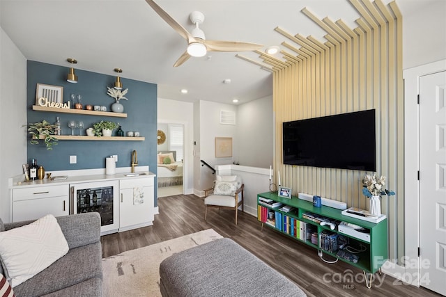 living room with bar area, dark wood-type flooring, ceiling fan, and beverage cooler