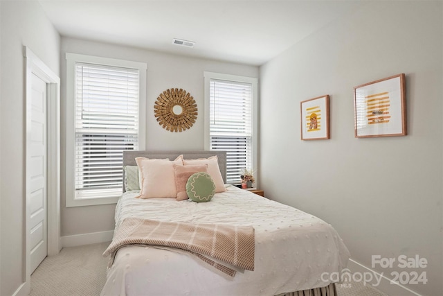 bedroom with light carpet and multiple windows