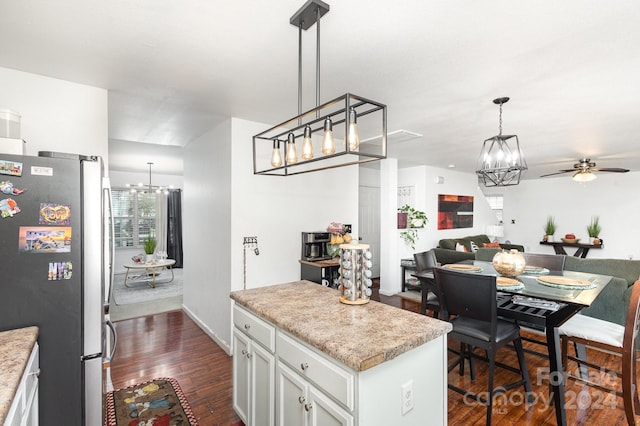 kitchen with stainless steel refrigerator, pendant lighting, white cabinets, dark wood-type flooring, and a center island