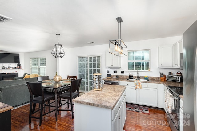 kitchen with a kitchen island, white cabinets, decorative light fixtures, and stainless steel appliances