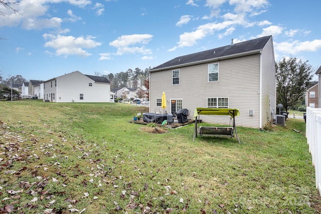 rear view of property featuring central air condition unit and a yard