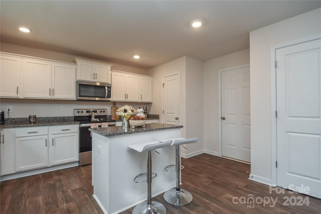 kitchen with white cabinets, appliances with stainless steel finishes, a center island, and dark hardwood / wood-style flooring