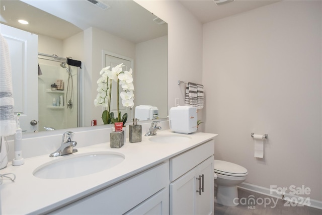 bathroom featuring vanity, a shower with shower door, and toilet