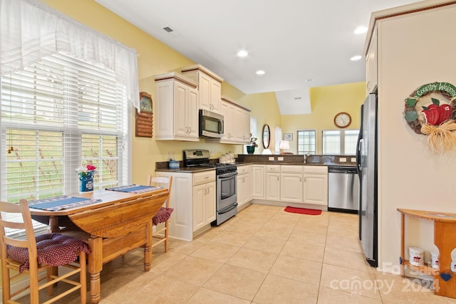 kitchen featuring stainless steel appliances, a wealth of natural light, light tile patterned floors, and sink