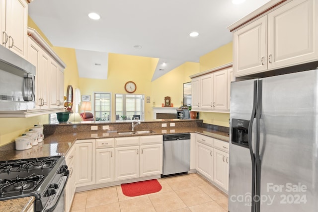 kitchen featuring light tile patterned flooring, sink, kitchen peninsula, appliances with stainless steel finishes, and dark stone countertops