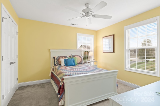 bedroom featuring a closet, light colored carpet, and ceiling fan