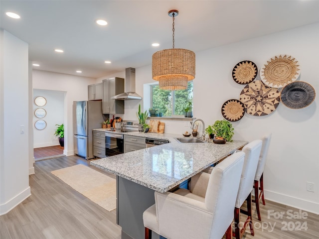 kitchen featuring sink, hanging light fixtures, wall chimney range hood, kitchen peninsula, and gray cabinets