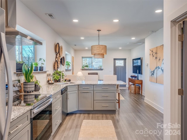 kitchen featuring kitchen peninsula, sink, appliances with stainless steel finishes, and light hardwood / wood-style flooring