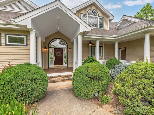 entrance to property with a shingled roof and a porch