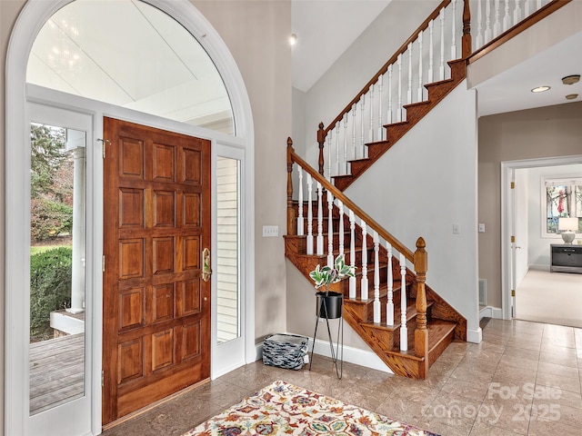 foyer entrance with stairway, baseboards, and visible vents