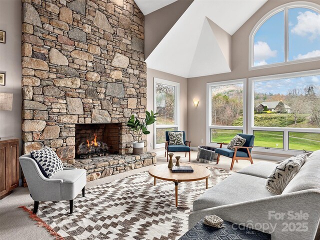 living room with high vaulted ceiling, a healthy amount of sunlight, and a stone fireplace