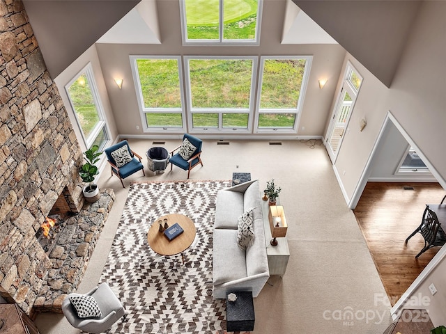 living area with a high ceiling, a fireplace, wood finished floors, visible vents, and baseboards